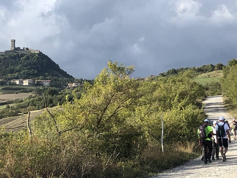 la Rocca di Radicofani in lontananza e il gruppo che cammina verso il paese